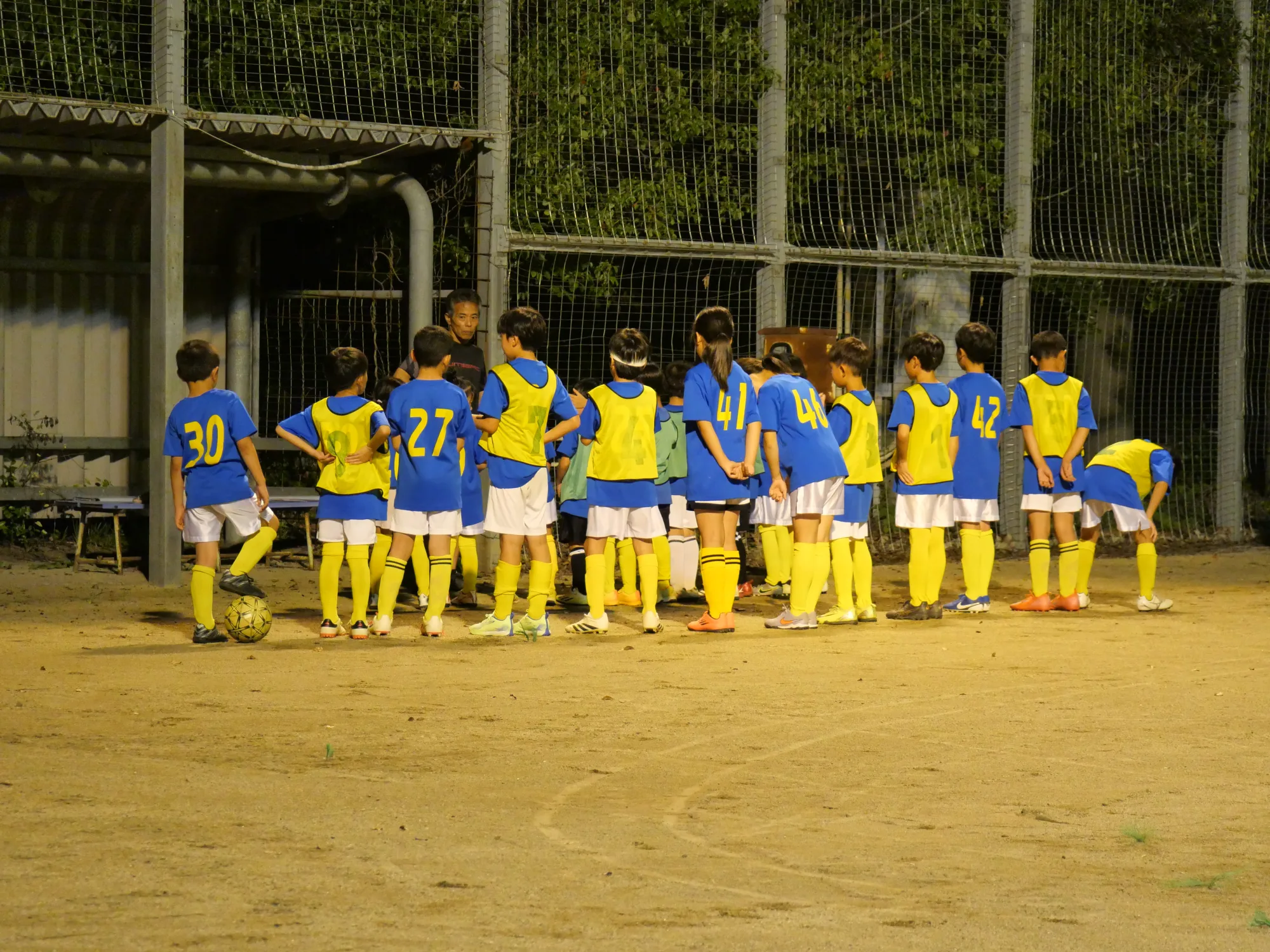 朝倉球場でコーチの話を聞くFC朝倉の選手たち